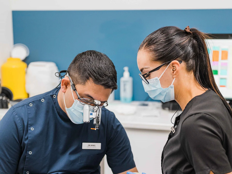 An endodontist and an assistant working together in a treatment room